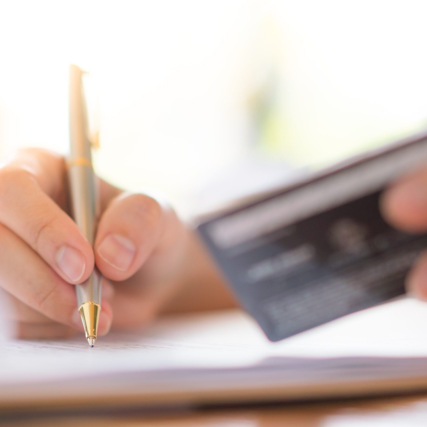Hand with pen and credit card over application form . Hand with pen and credit card over application form .