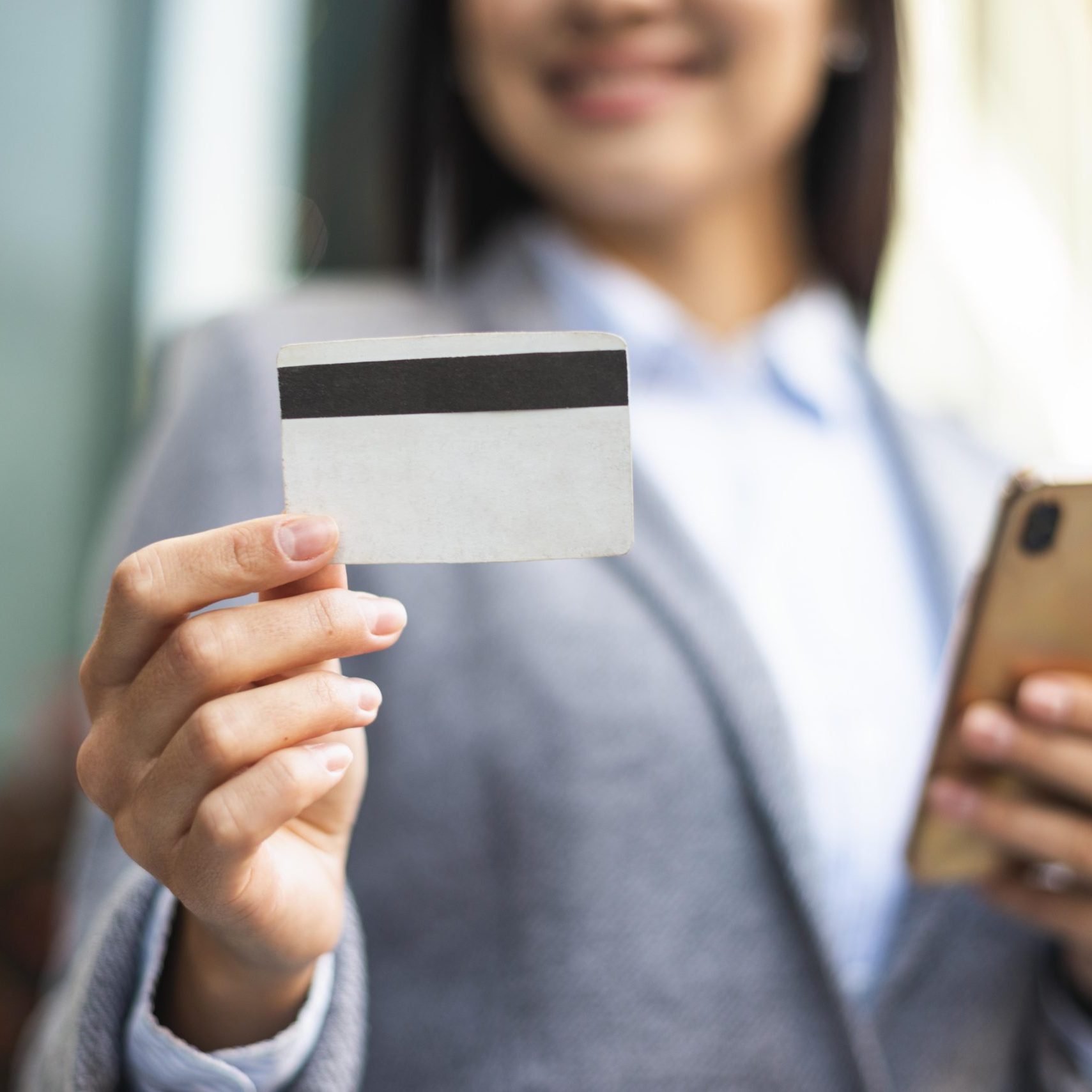 smiley-businesswoman-with-smartphone-credit-card-outdoors