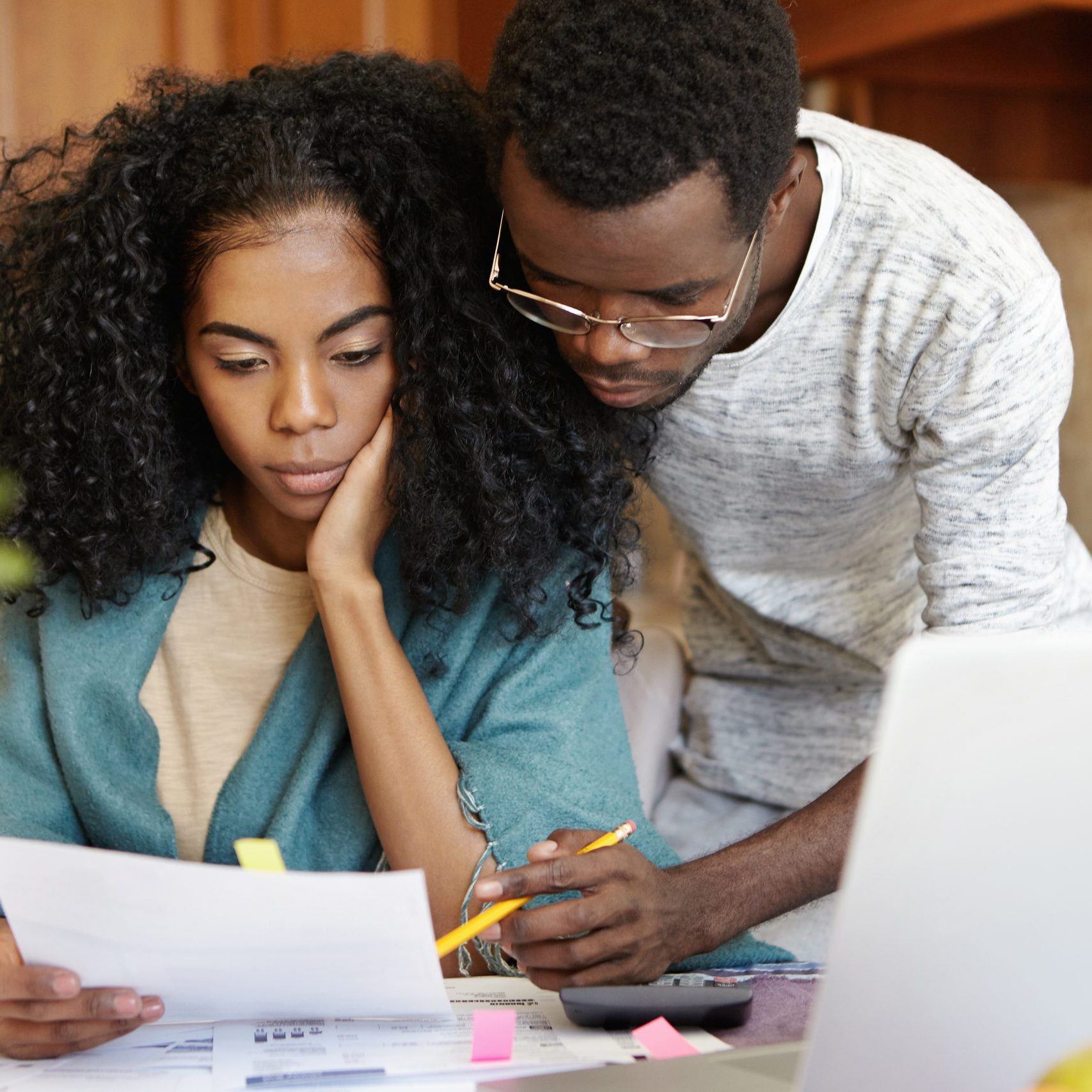 Family, domestic budget, economy and finances concept. Stressed young African-American couple working through paperwork together, calculating expenses, trying to save some money on new big purchase