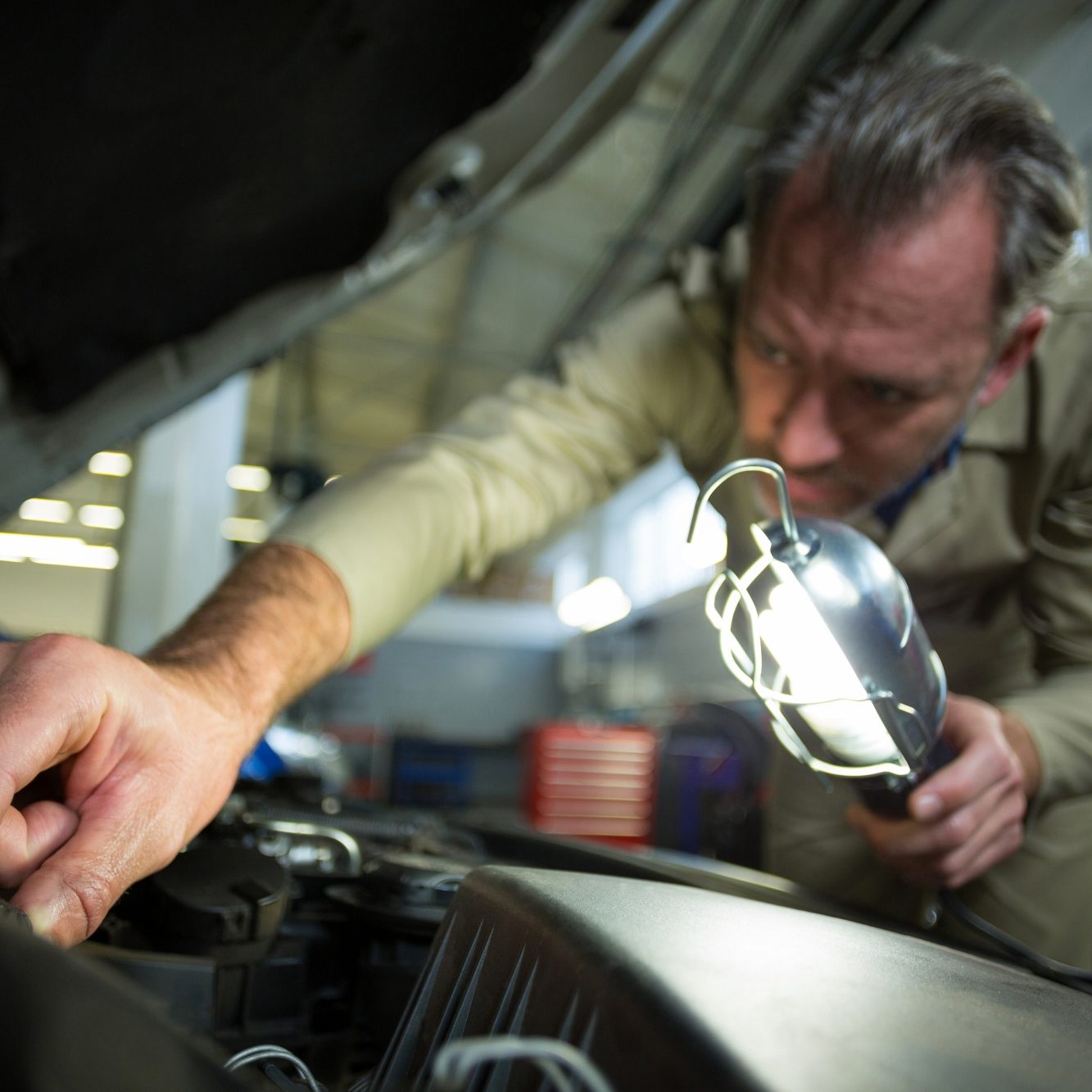 mechanic-examining-car-with-lamp
